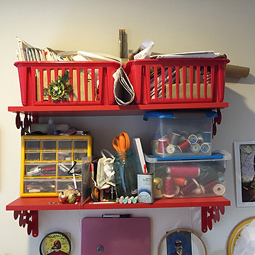 The baskets on the top shelf are full of patterns and the bottom shelf holds her tools, notions, and threads.